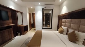 Een moderne hotelkamer met een groot bed, een flatscreen televisie, een houten kaptafel en een inloopkast.