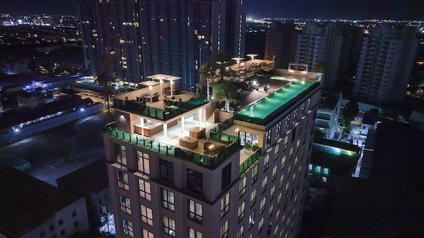 Un immeuble de grande hauteur doté d’une terrasse sur le toit, comprenant un espace de détente extérieur et une piscine.