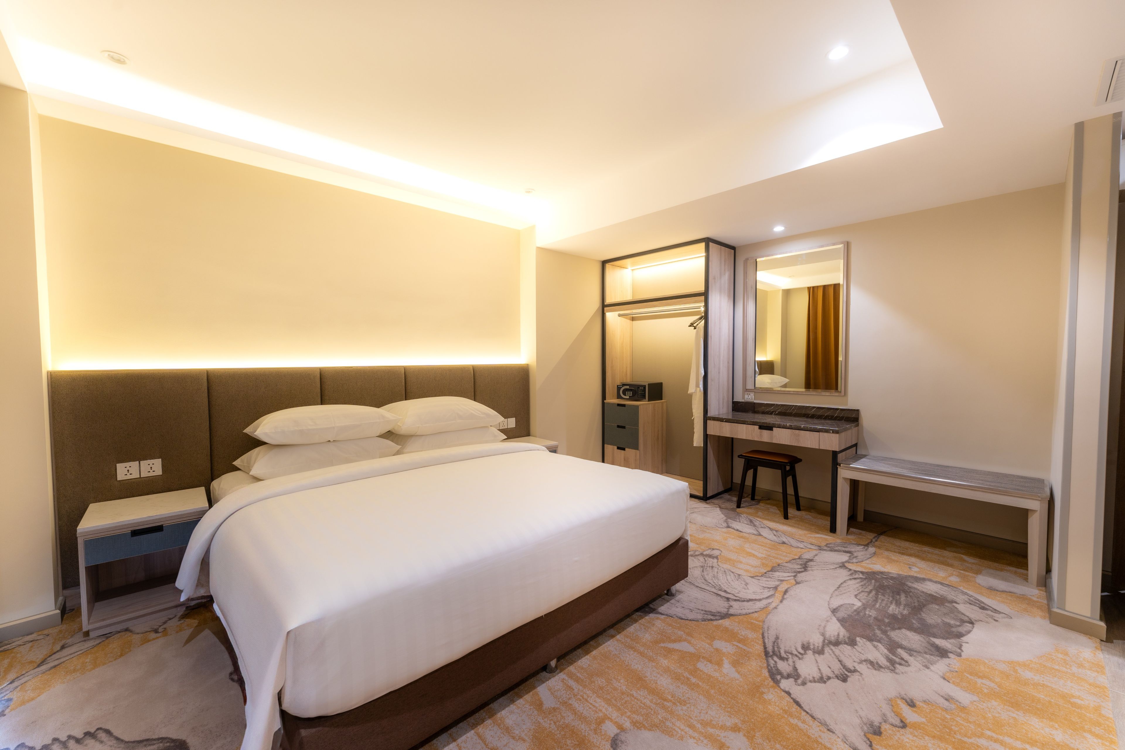Una habitación de hotel con una cama grande, un escritorio, un espejo y un vestidor.