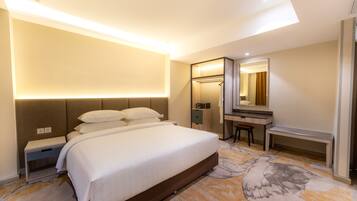Una habitación de hotel con una cama grande, un escritorio, un espejo y un vestidor.