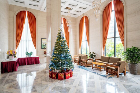 A spacious lobby with a large Christmas tree, elegant furniture, and large windows with draped curtains. - The Skye Phnom Penh Hotel & Apartments (Phnom Penh)