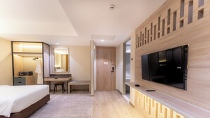 Een moderne hotelkamer met een bed, bureau, stoel, televisie en een inloopkast.