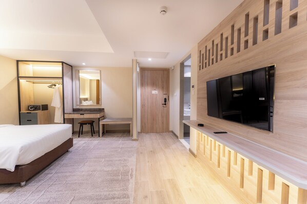 Una habitación de hotel moderna con cama, escritorio, silla, televisión y vestidor.