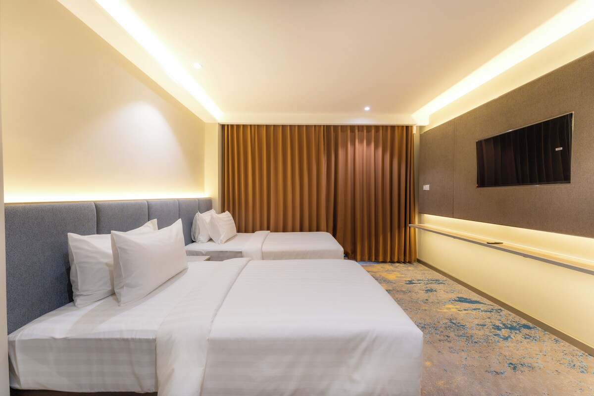A hotel room with two beds, a large mirror, and a wall-mounted TV.