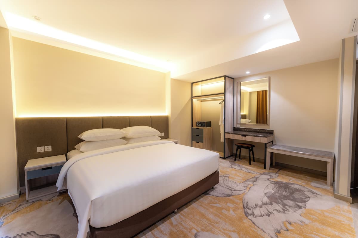 Ein Hotelzimmer mit einem großen Bett, einem Schreibtisch, einem Spiegel und einem Kleiderschrank.