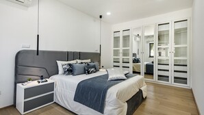 A modern bedroom with a large bed, bedside tables, a wardrobe, and a ceiling-mounted air conditioner. - Flor de Lis - VIP Properties by Interhome (Paderne)