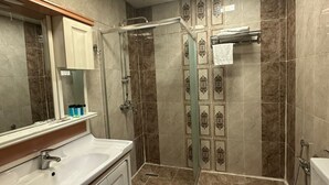 A bathroom with a shower, toilet, and vanity with a mirror. - Raymond Hotel (Baku)