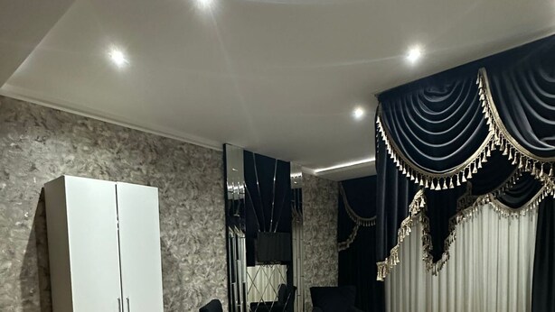 A modern bedroom with a bed, a wardrobe, two armchairs, and a small table. - Raymond Hotel (Baku)
