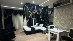 A modern living room with a sofa, a dining table, and a large mirror. - Raymond Hotel (Baku)