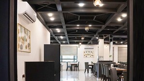 Un espacio de oficina moderno con una mesa larga y sillas, un panel negro y un equipo de aire acondicionado en la pared.