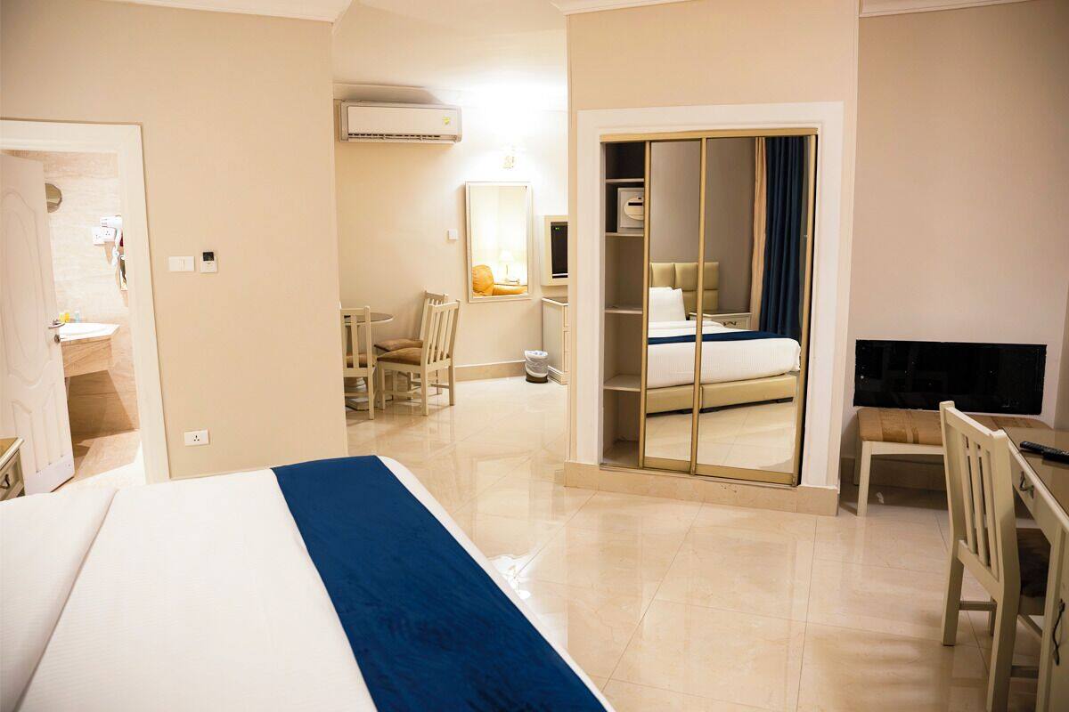 Una habitación de hotel con cama, escritorio, silla, armario y televisor.