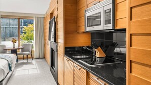 A modern kitchen with wooden cabinetry, a black countertop, and stainless steel appliances. - Luxury Resort Ski In Ski Out Studio (Snowmass Village)