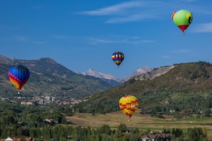 Una valle con montagne, mongolfiere e un paese sullo sfondo.