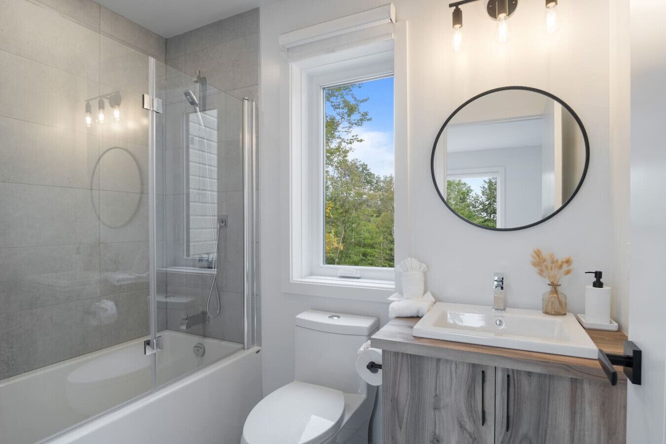 A modern bathroom with a glass-enclosed shower, a toilet, a sink with a wooden vanity, and a large mirror.
