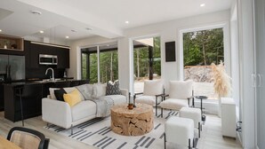 A modern living room with a white sofa, a coffee table, and a view of the outdoors.