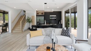 A modern living room with a sofa, coffee table, and a kitchen area with a microwave and cabinets.