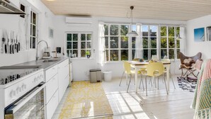 Une cuisine lumineuse, avec des meubles blancs, une cuisinière en acier inoxydable et une fenêtre donnant sur un espace verdoyant.