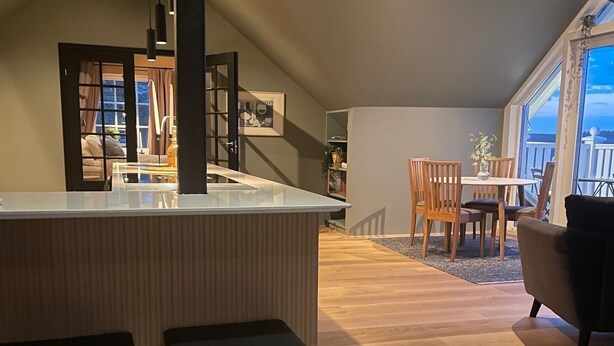 A modern kitchen with a central island, bar stools, and a dining area with wooden chairs. - Panoramic view near Gbg and nature (Västra Götalands län)