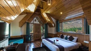 Une chambre confortable, avec un plancher en bois, un grand lit, une petite table et une vue sur l’extérieur.