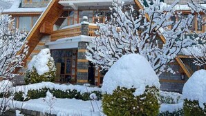 Un chalet doté d’un toit à forte pente, de balcons en bois et d’une façade en pierre.