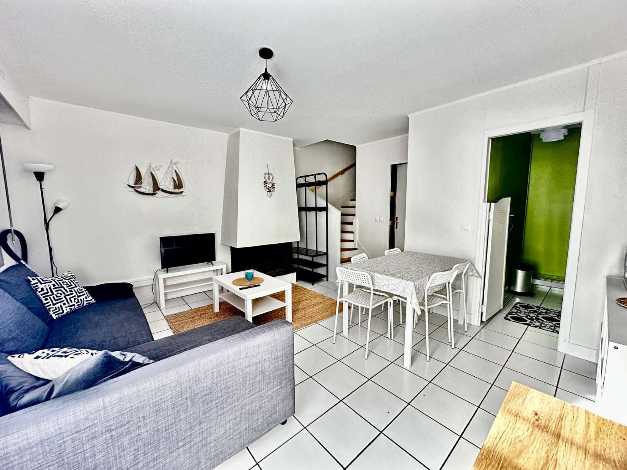 A modern living room with a sofa, TV, and a dining table with chairs.