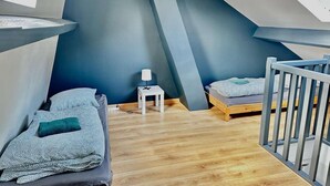 A compact, sloped ceiling room with two beds, a small table, and a railing. - La "Casita", triplex with garden near the center of town (Courseulles-sur-Mer)