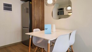 Een moderne keuken met een witte tafel, witte stoelen, een houten kast en een magnetron.
