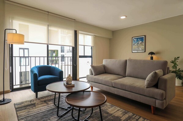 A modern living room with a sofa, a blue armchair, a round coffee table, and a floor lamp.