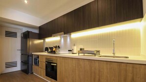 A modern kitchen with wooden cabinets, stainless steel appliances, and a built-in oven. - w* | Comfy 2BR w/ Balcony Near Larcomar (Miraflores)