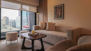 A modern living room with a sofa, armchairs, a coffee table, and a large window offering a city view. - w* | Comfy 2BR w/ Balcony Near Larcomar (Miraflores)