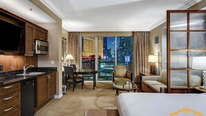 A hotel room with a kitchen, dining area, and a large bed. - Premium Studio | Jacuzzi, Balcony & Strip View (Las Vegas)