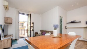 A modern living room with a wooden dining table, white chairs, a sofa, and a TV. - VivimiHome - Stelvio House (Milano)