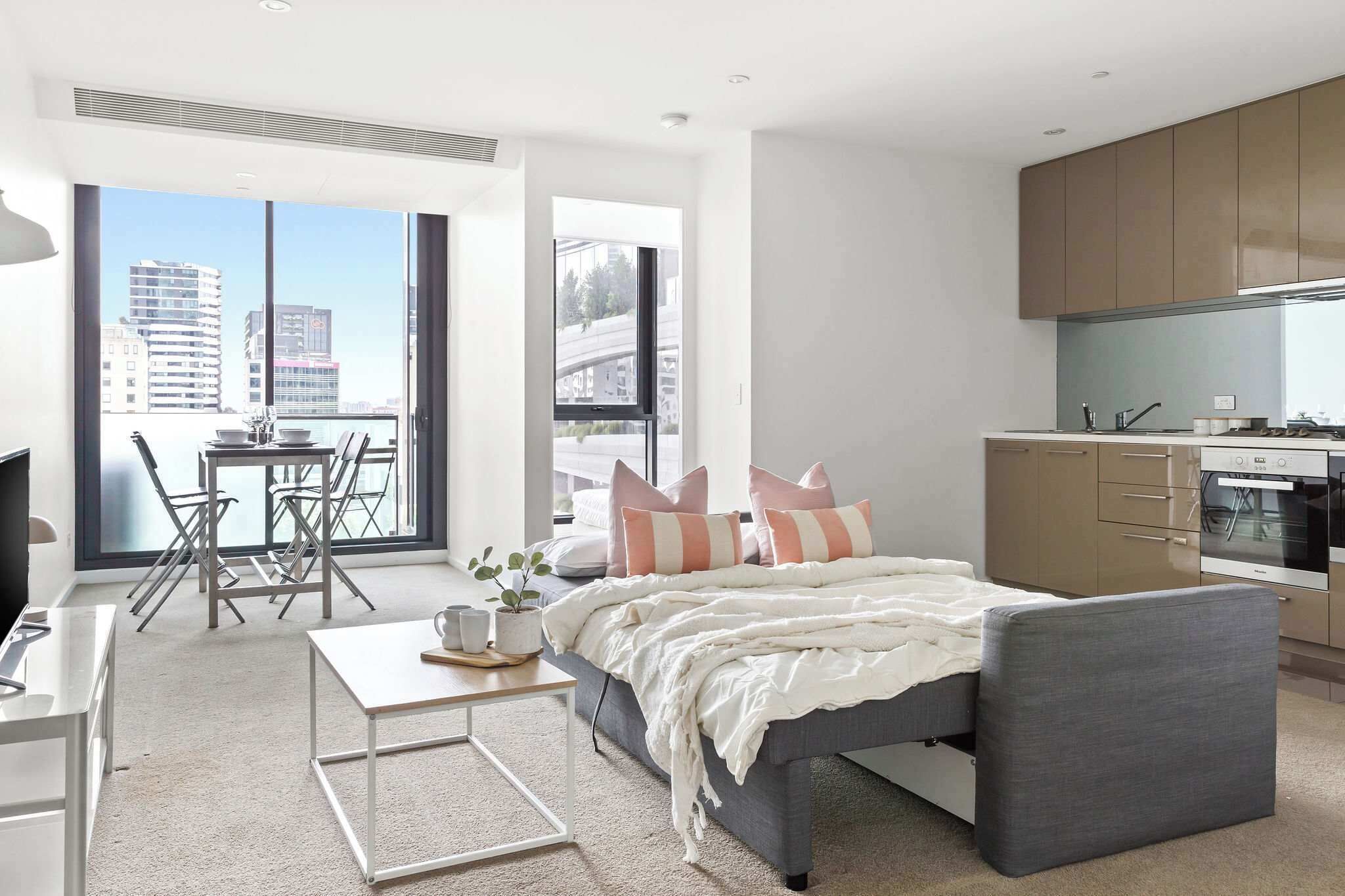 A modern bedroom with a bed, bedside table, and a view of the city through large windows.