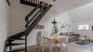 A modern living space with a staircase, a dining area, and a sofa. - Cozy apartment in a former farm within walking distance of the center of Workum (Workum)