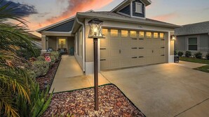 Una casa residenziale con garage, un cartello accogliente e un giardino curato.