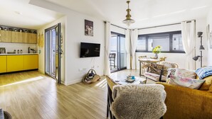 Un salon moderne avec un canapé, une table à manger et un téléviseur fixé au mur.