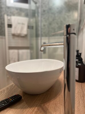 A bathroom with a white basin, a faucet, and a remote control on the counter. - La Cascina di Bea (Torre Boldone)