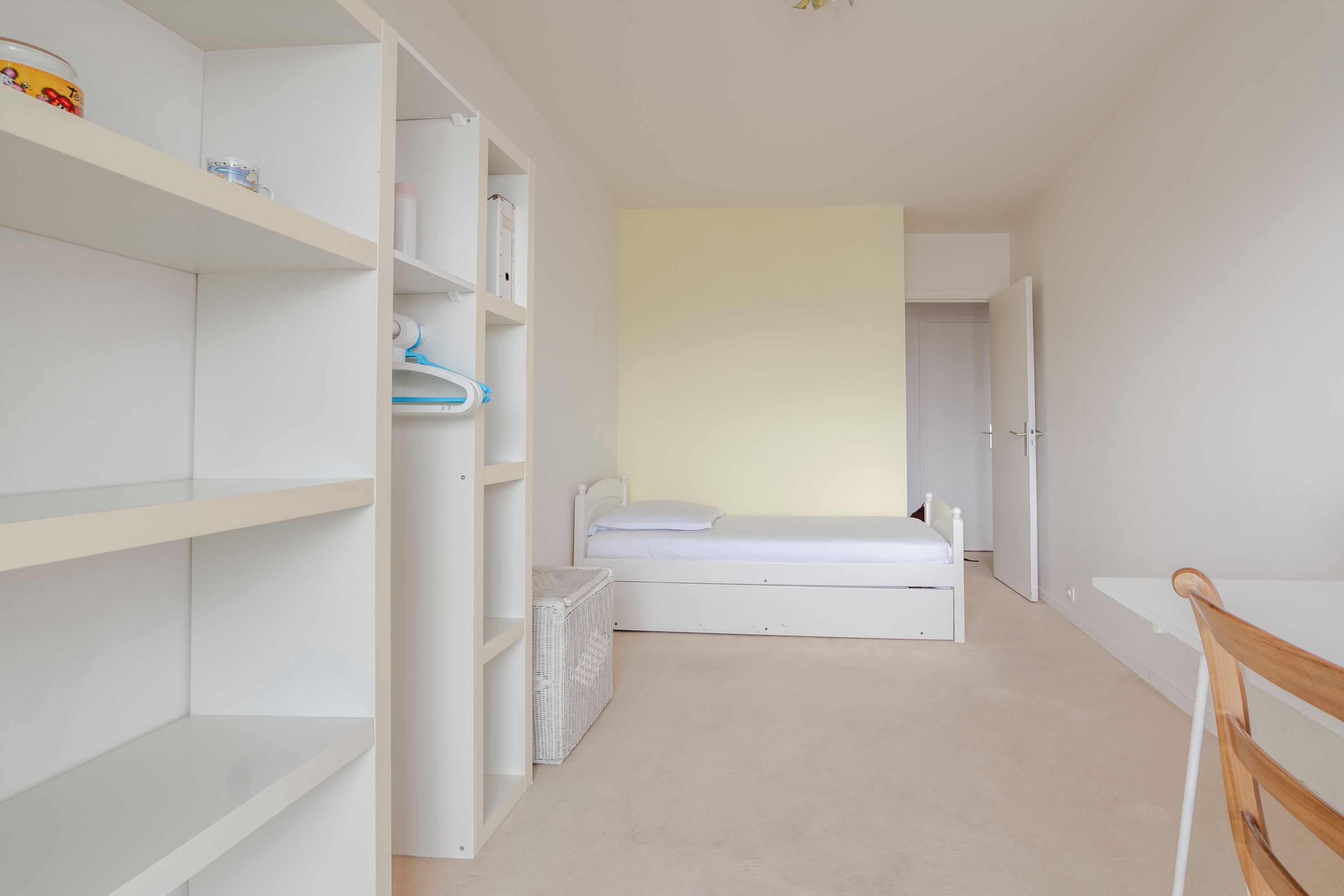 Une chambre avec un lit simple, une armoire blanche et un petit bureau.