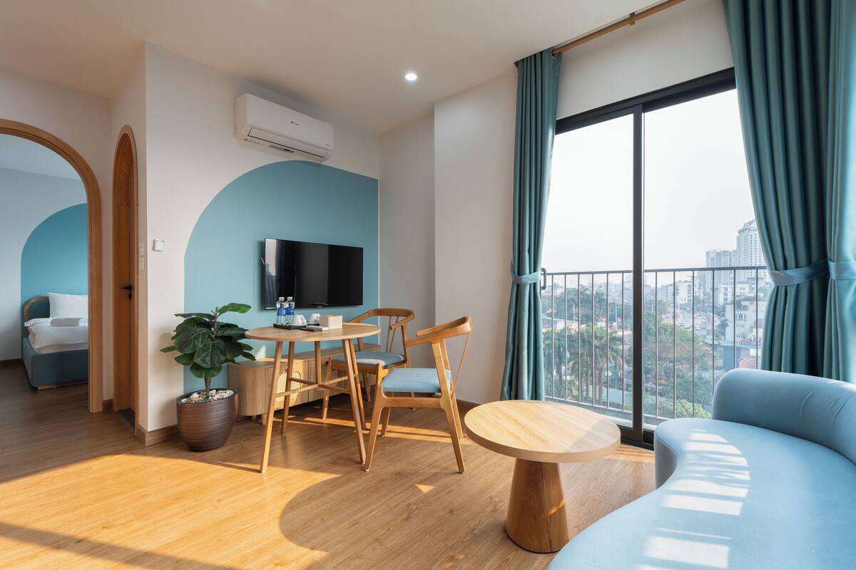 Un salon moderne comprenant un coin repas, un canapé, un téléviseur et un balcon offrant une vue sur la ville.