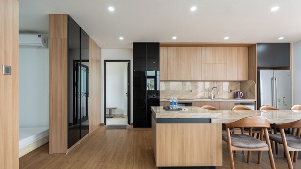 Una cocina moderna con armarios de madera, una isla central y un comedor con sillas.