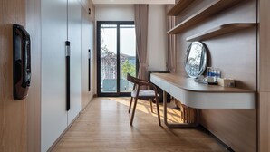 Una habitación de hotel moderna con suelo de madera, un escritorio con espejo y un acceso corredizo a un balcón.