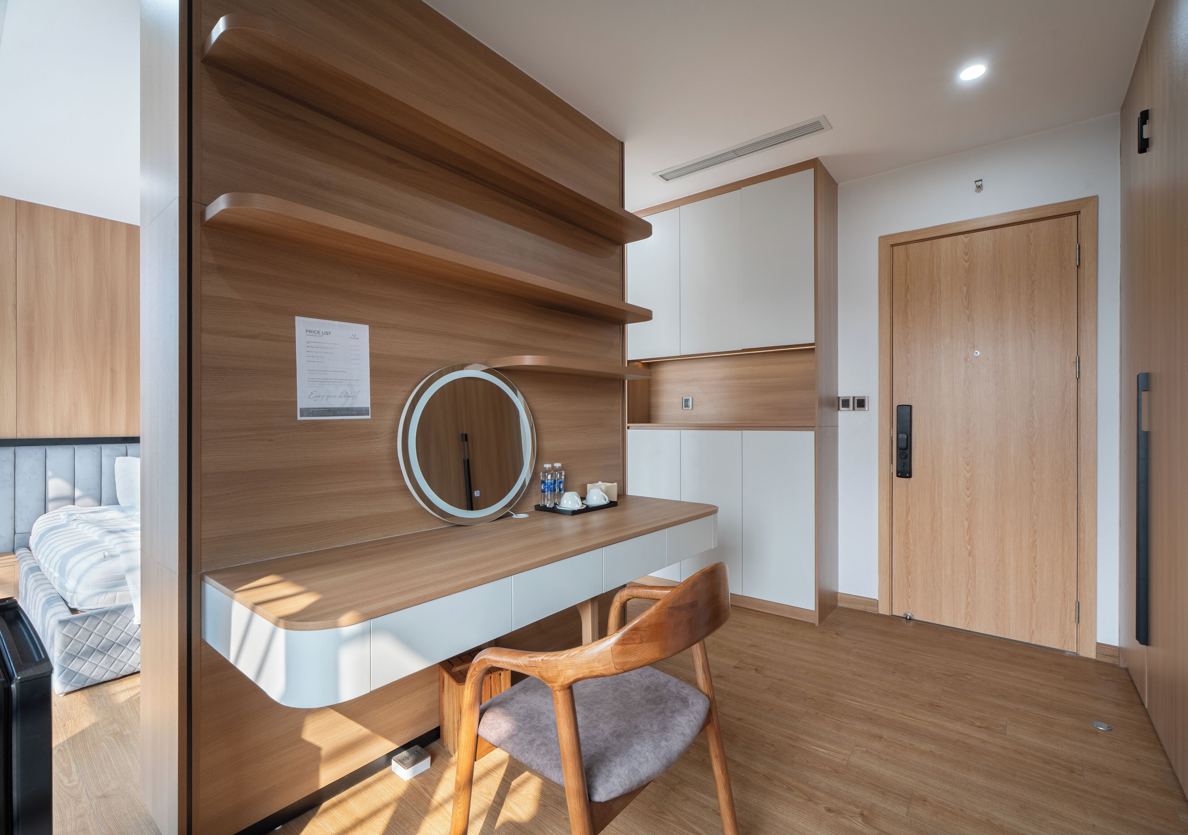 A modern bedroom with a wooden desk, a chair, a bedside table, and a wardrobe.