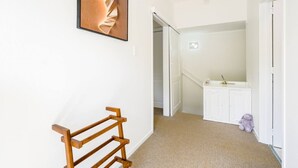 A hallway with a wooden bench, a white door, and a white cabinet with a teddy bear. - Enjoy Your Private SPA with Stunning Tranquil View (Auckland)