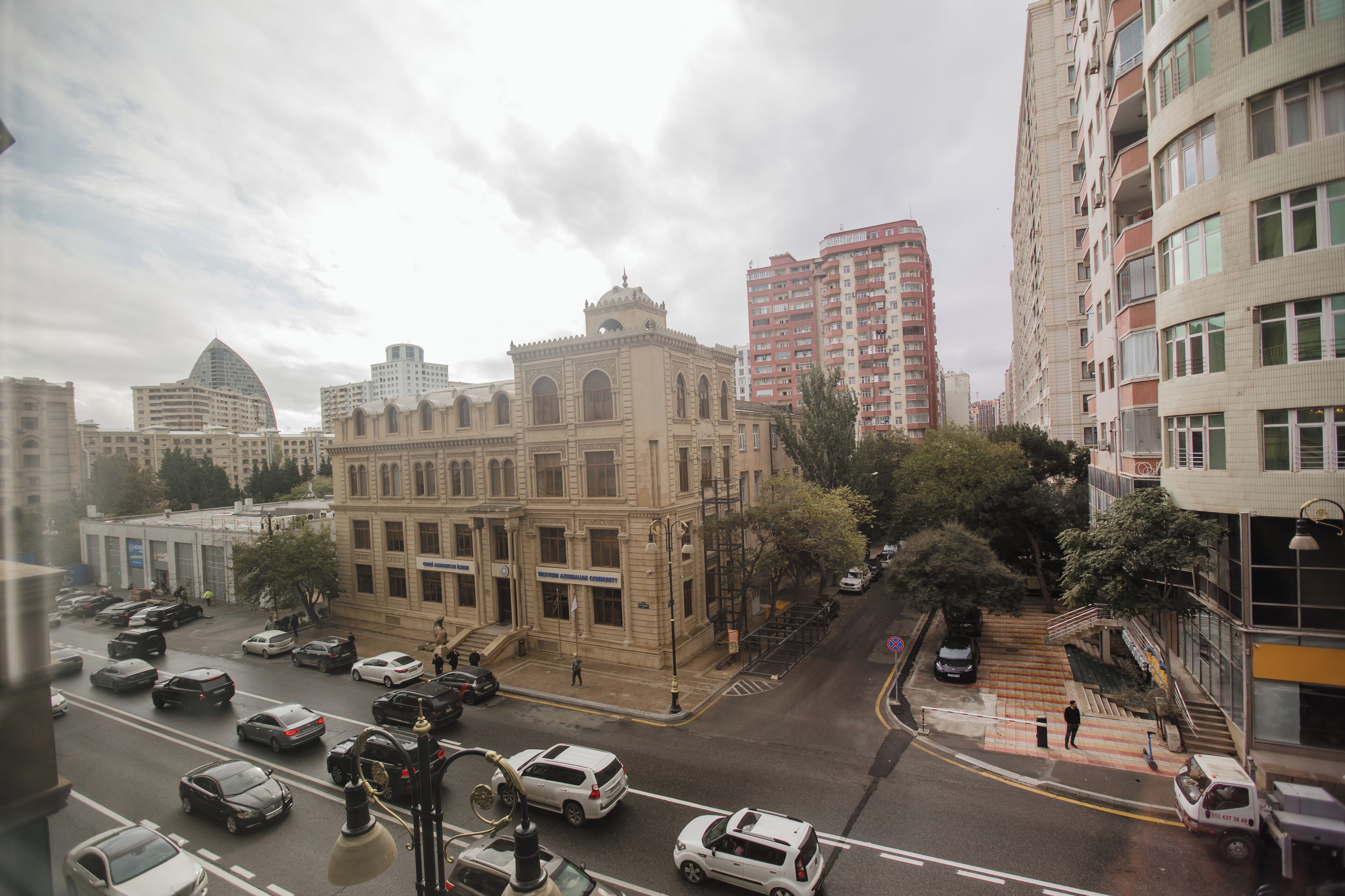 Une rue de la ville avec un bâtiment historique, des immeubles modernes et des voitures garées.