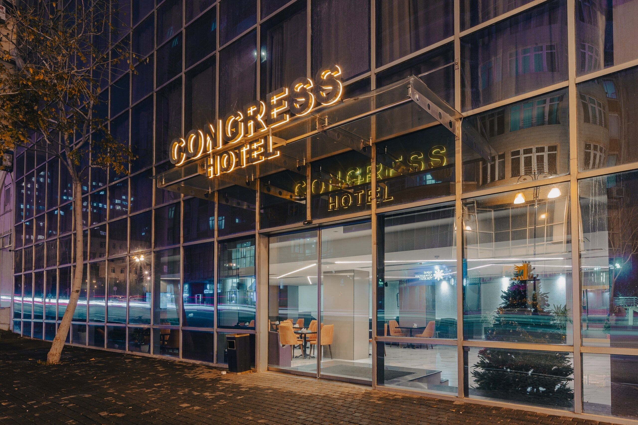 Um hotel moderno com grandes janelas de vidro e um letreiro de neon que diz 'CONGRESS HOTEL'.