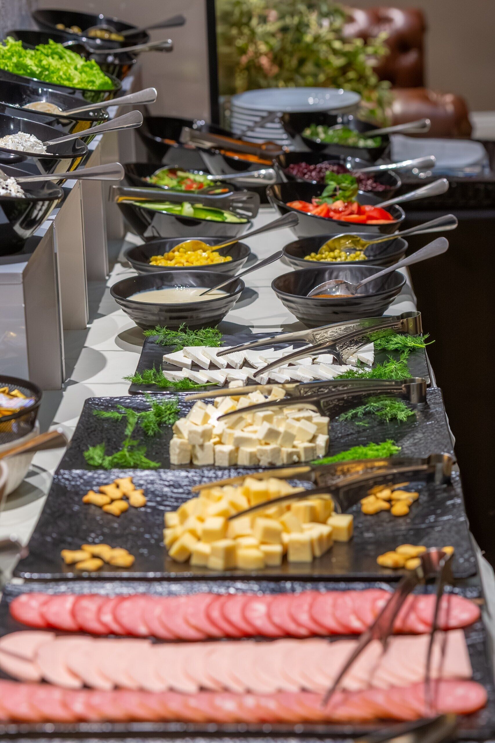 Een buffet met diverse soorten eten, waaronder vlees, kaas en groenten.