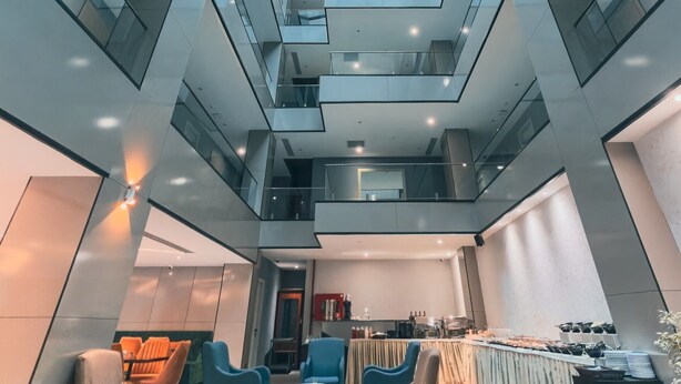 Een modern interieur met een glazen dak, verschillende niveaus en een eethoek met tafels en stoelen.