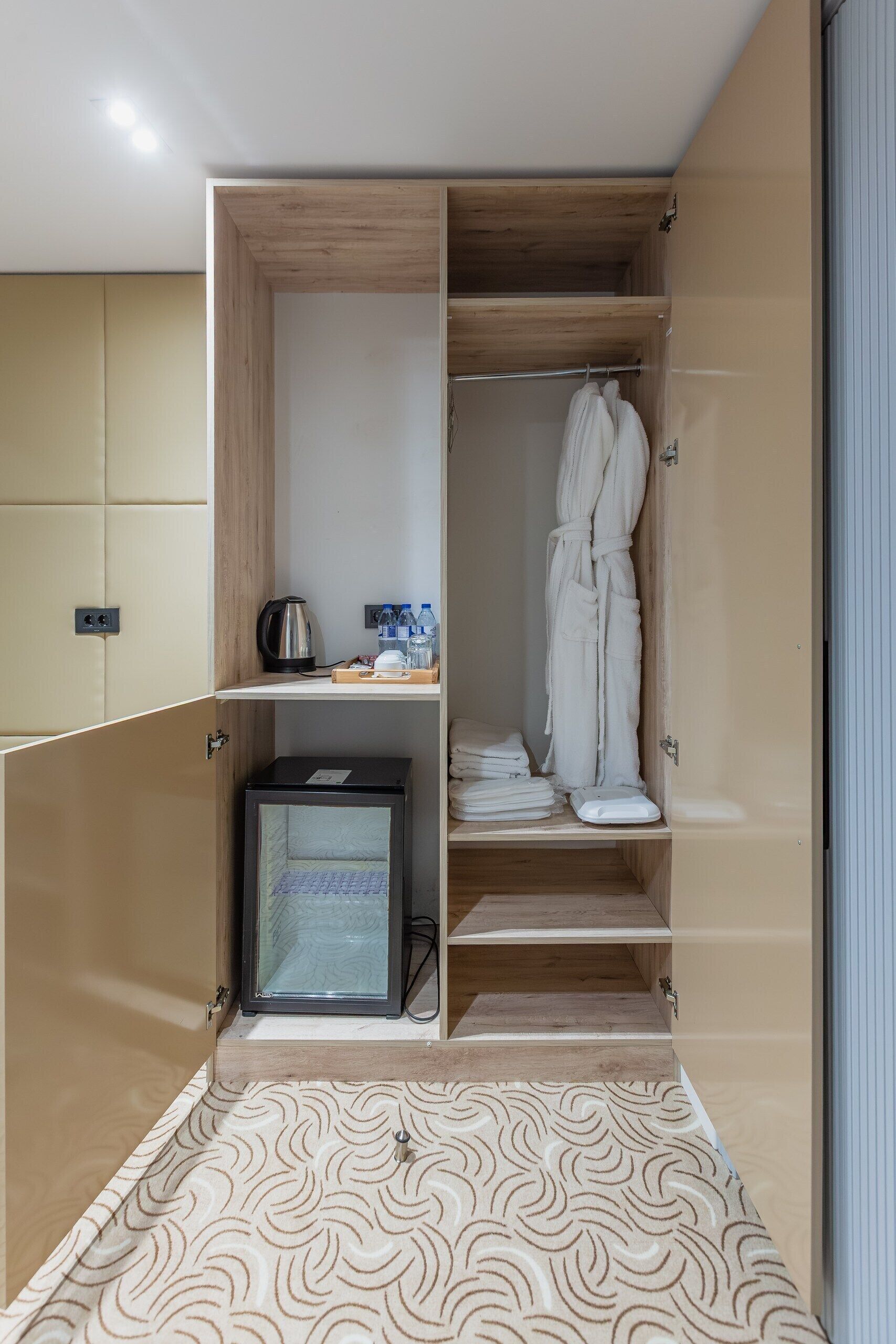 A modern bathroom with a walk-in shower, a towel rack, and a small cabinet with toiletries.