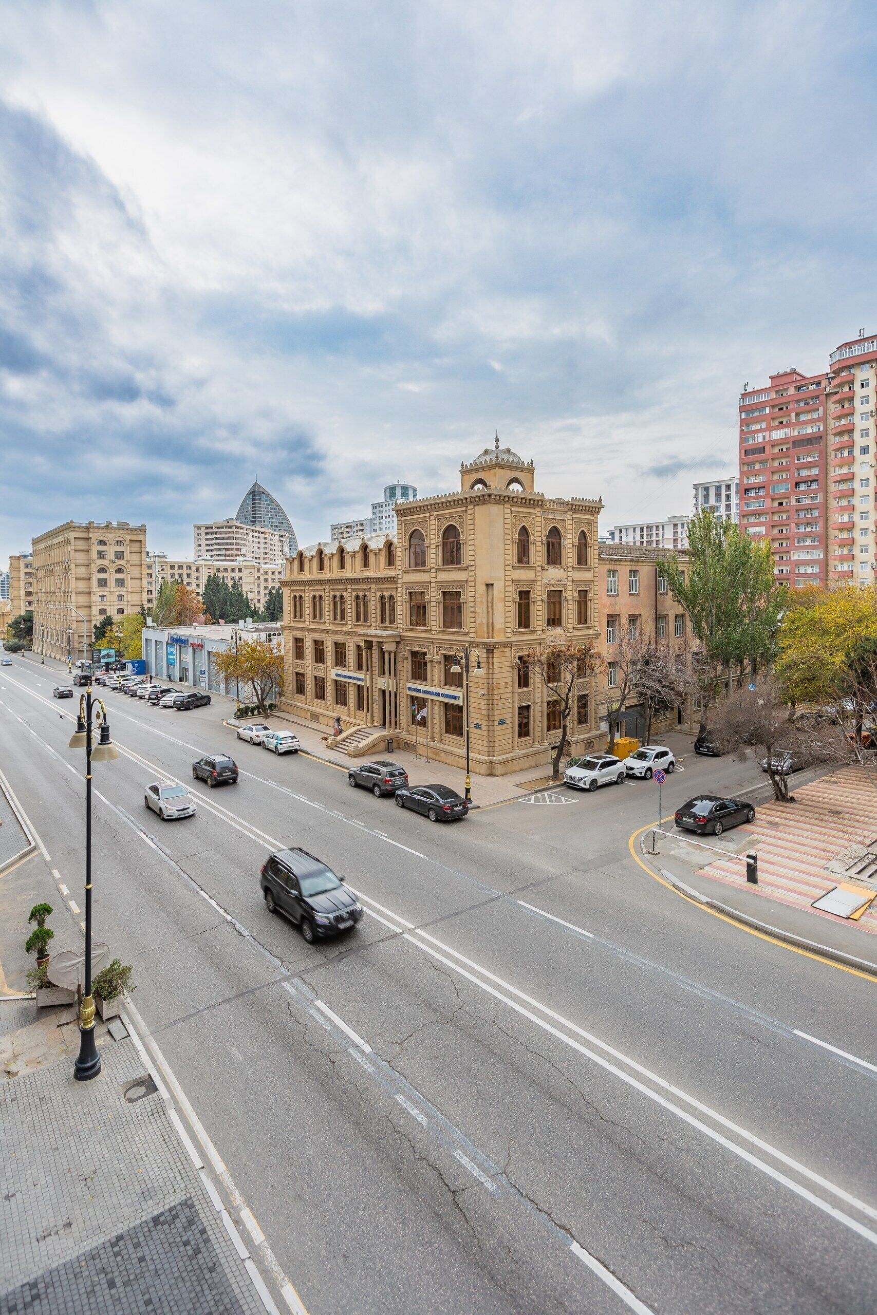 Un edificio de varios pisos con estilo arquitectónico clásico, situado en una intersección urbana con una avenida amplia y múltiples carriles.