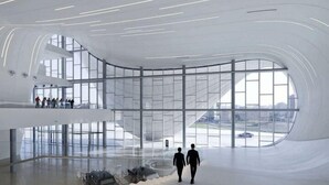 Een ruim, modern interieur met een gebogen plafond en grote ramen met uitzicht op de stad.